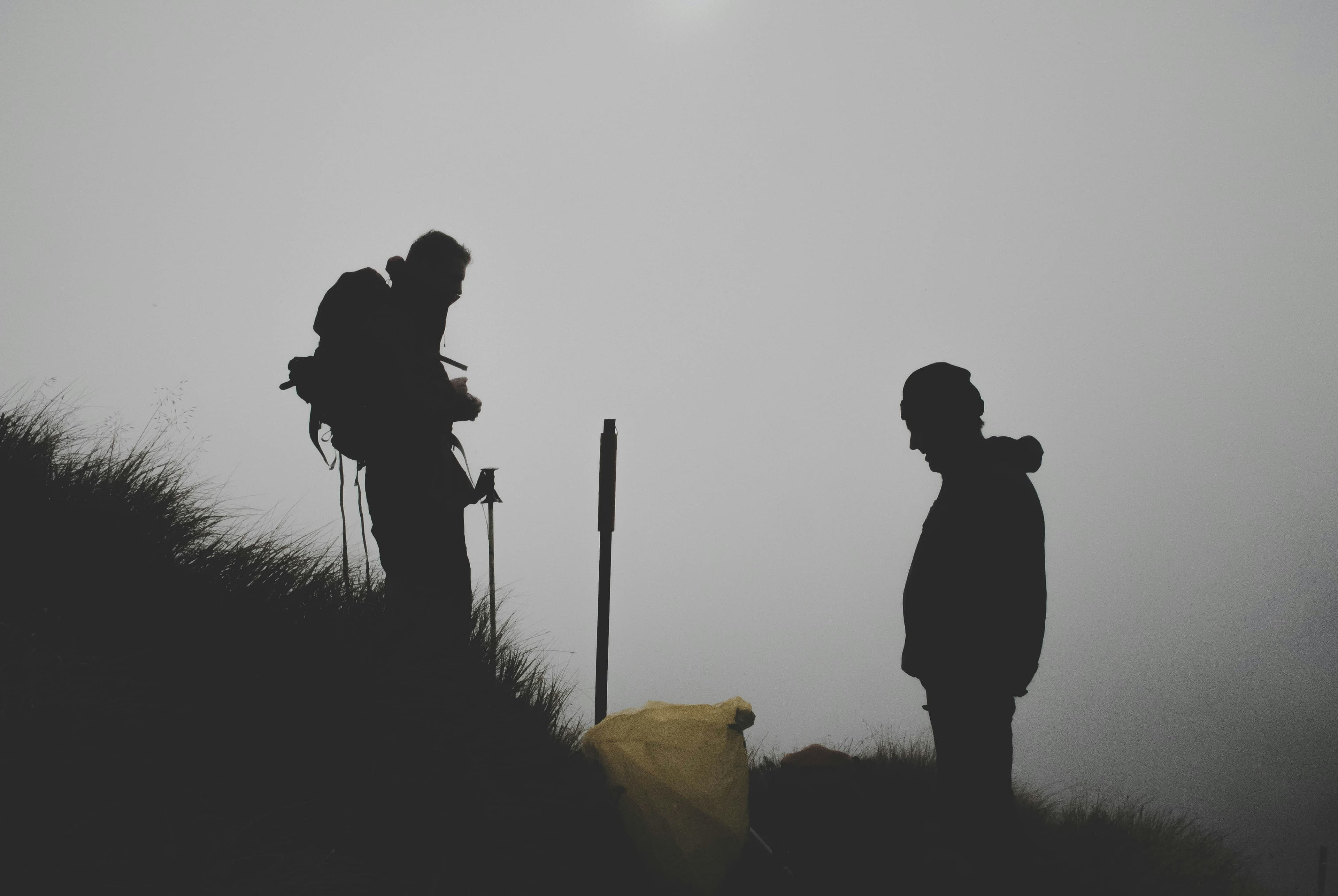 Two men climbing a mountain silhouette